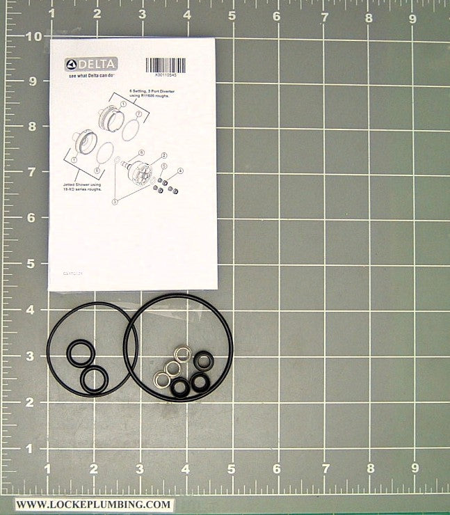 Delta cartridge repair kit with O-rings and metal components displayed next to instruction sheet on measurement grid.
