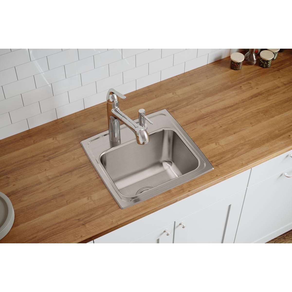 Stainless steel single bowl drop-in sink with one faucet hole, installed in wood countertop with white subway tile backsplash