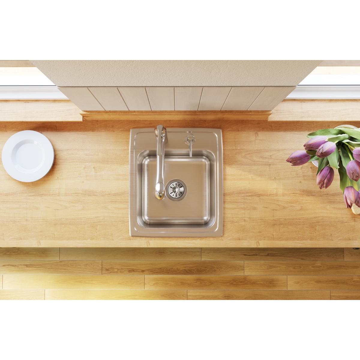 Stainless steel single bowl drop-in sink installed in wood countertop with faucet and drain strainer visible.