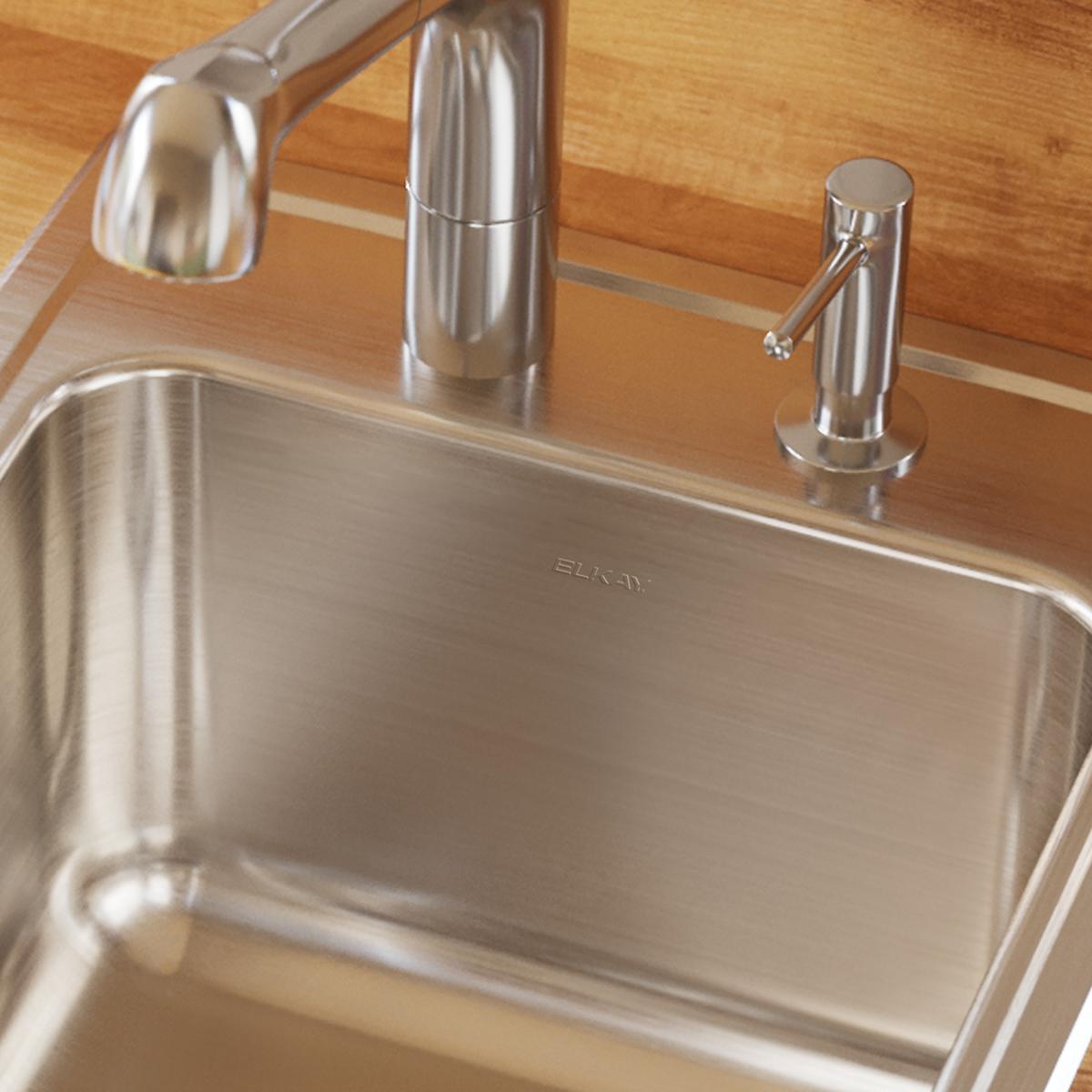 Stainless steel single bowl drop-in sink with brushed finish, installed in wood countertop with faucet and dispenser.