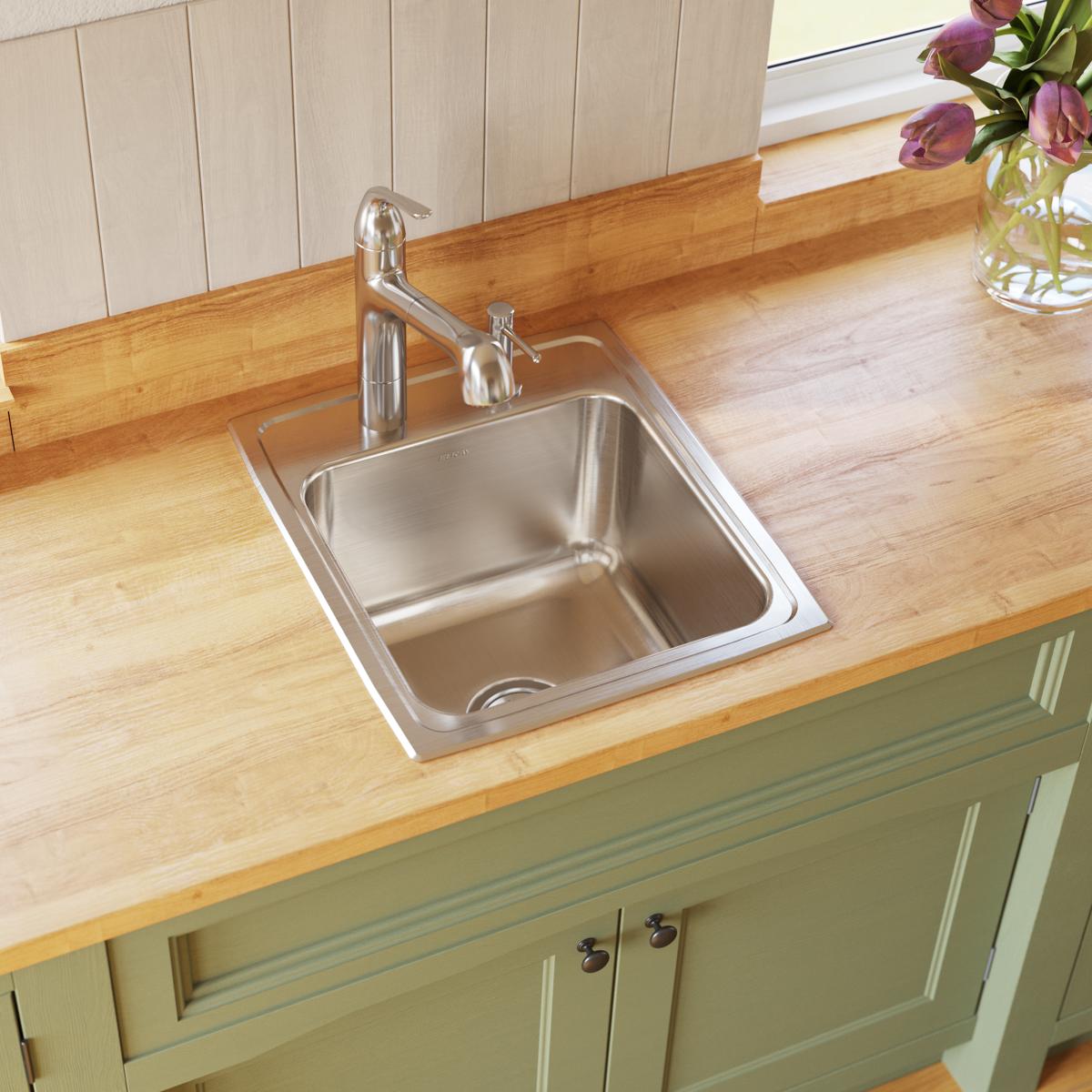 Stainless steel single bowl drop-in sink with three mounting holes, installed in wood countertop with chrome faucet.