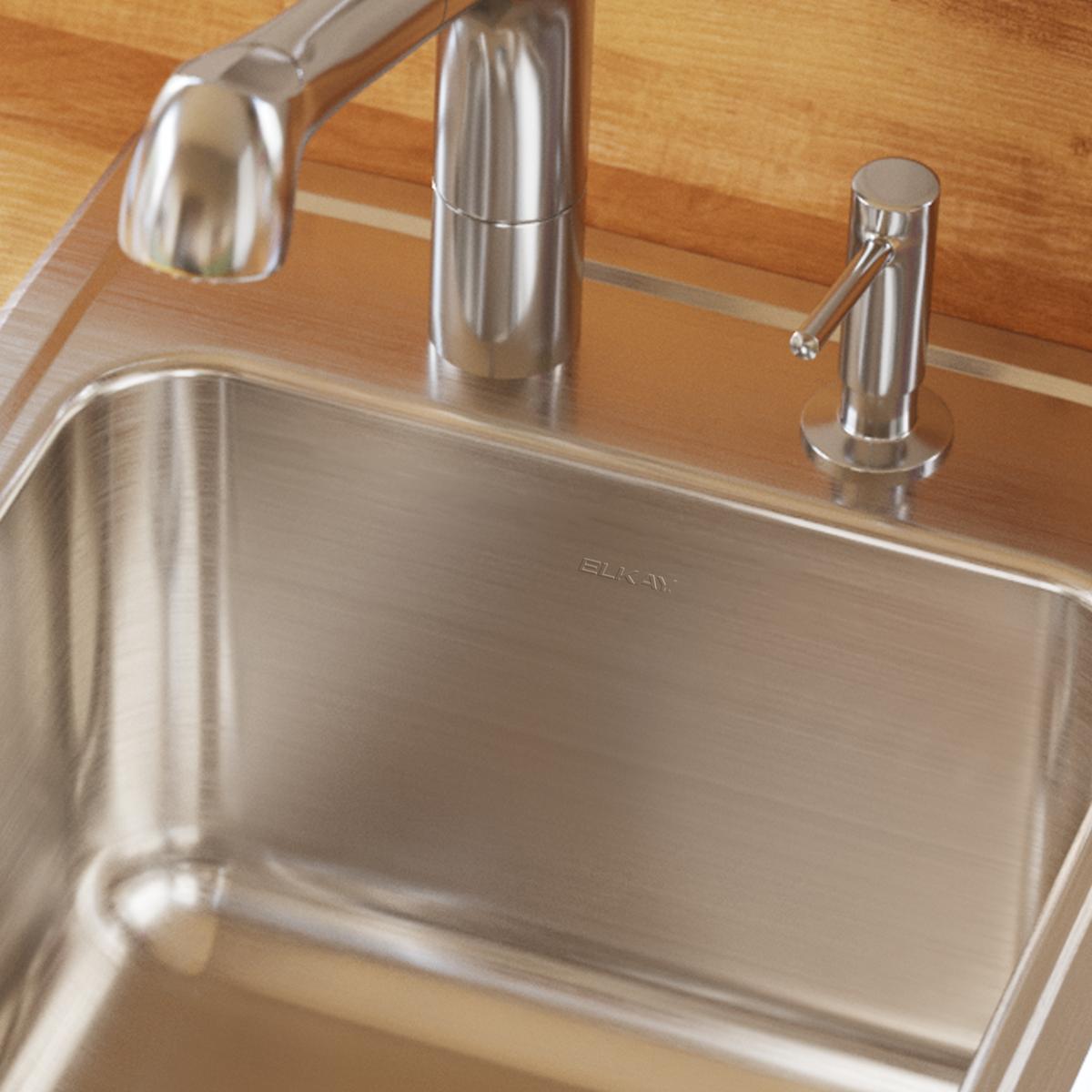 Stainless steel drop-in sink with single bowl, faucet, and spray attachment installed in wooden countertop.