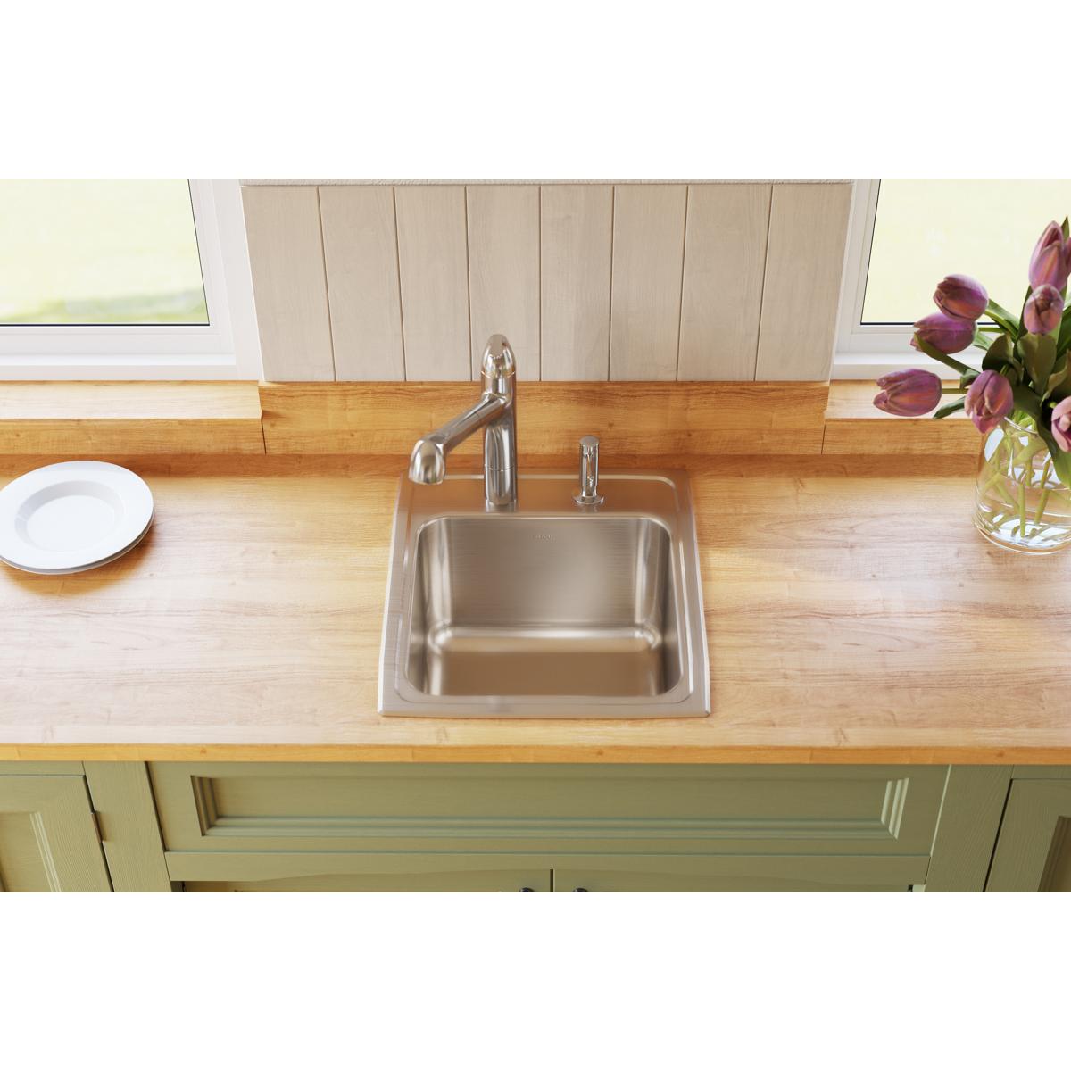 Stainless steel single bowl drop-in sink installed in wooden countertop with chrome faucet and two mounting holes.