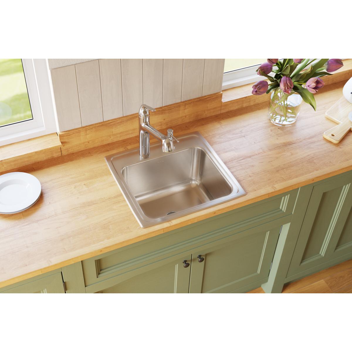 Stainless steel single bowl drop-in sink installed in wood countertop with chrome faucet.