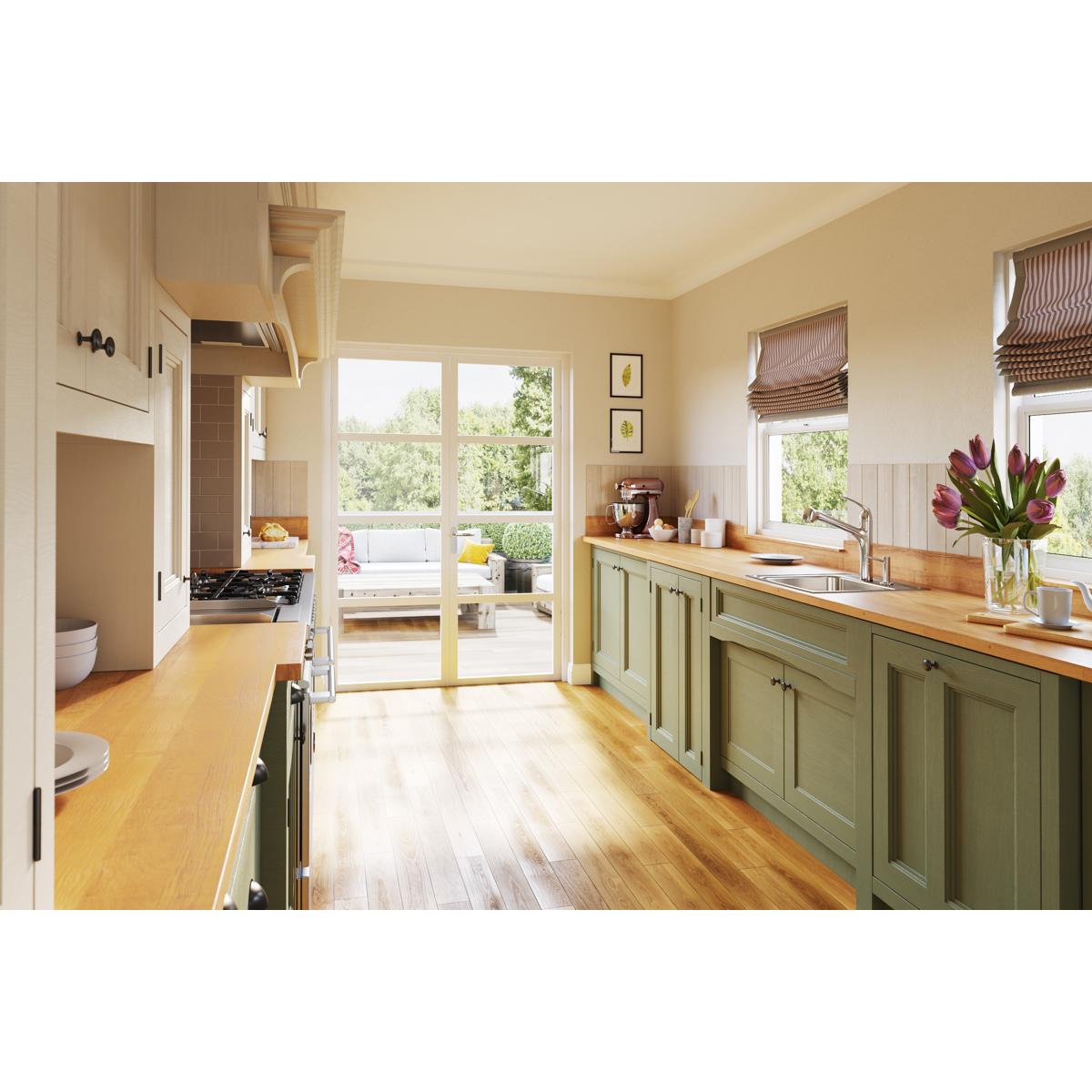 Stainless steel single bowl drop-in laundry sink installed in green cabinetry with wooden countertop in a bright kitchen.