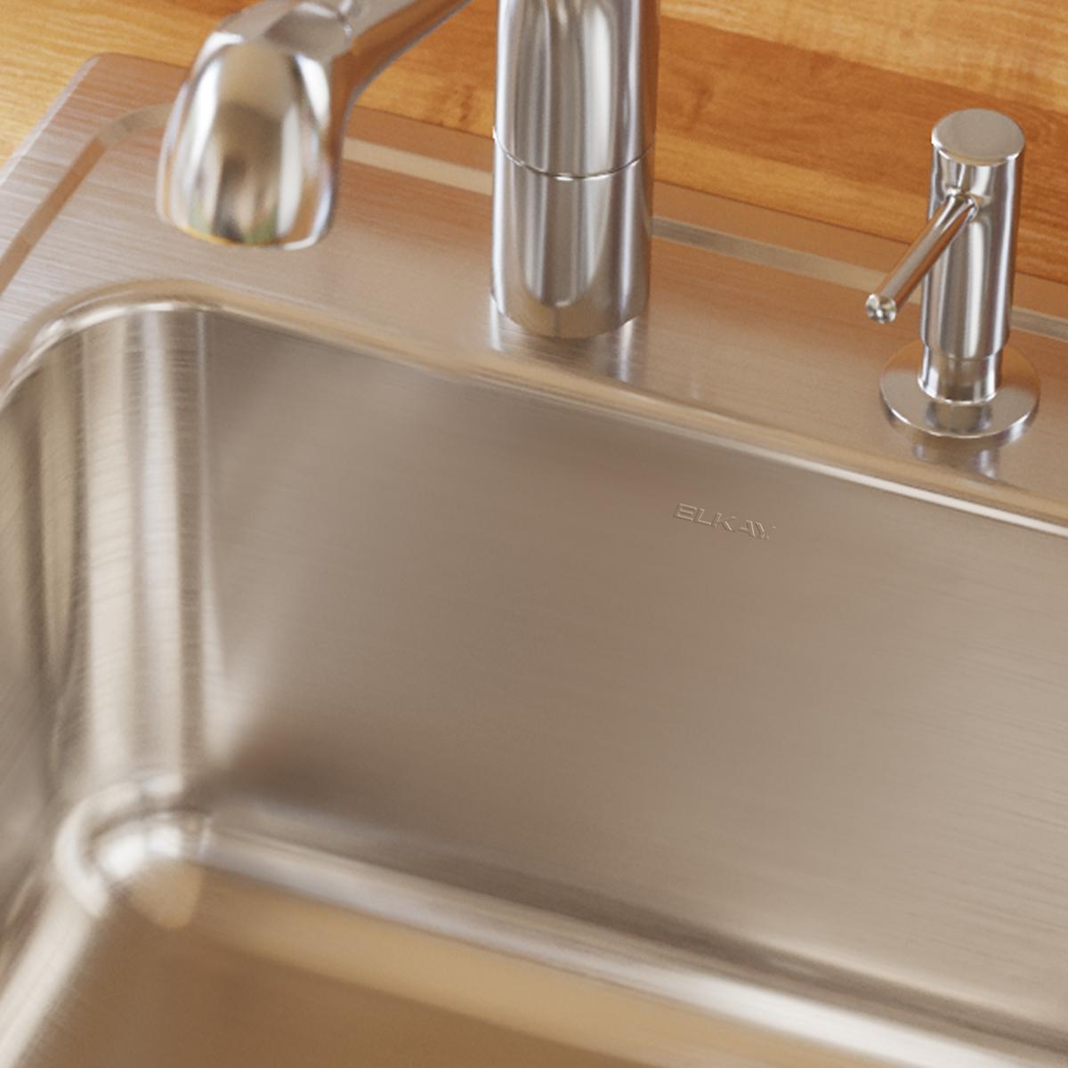 Stainless steel drop-in laundry sink with single bowl, three faucet holes, and brushed finish mounted in wooden countertop.