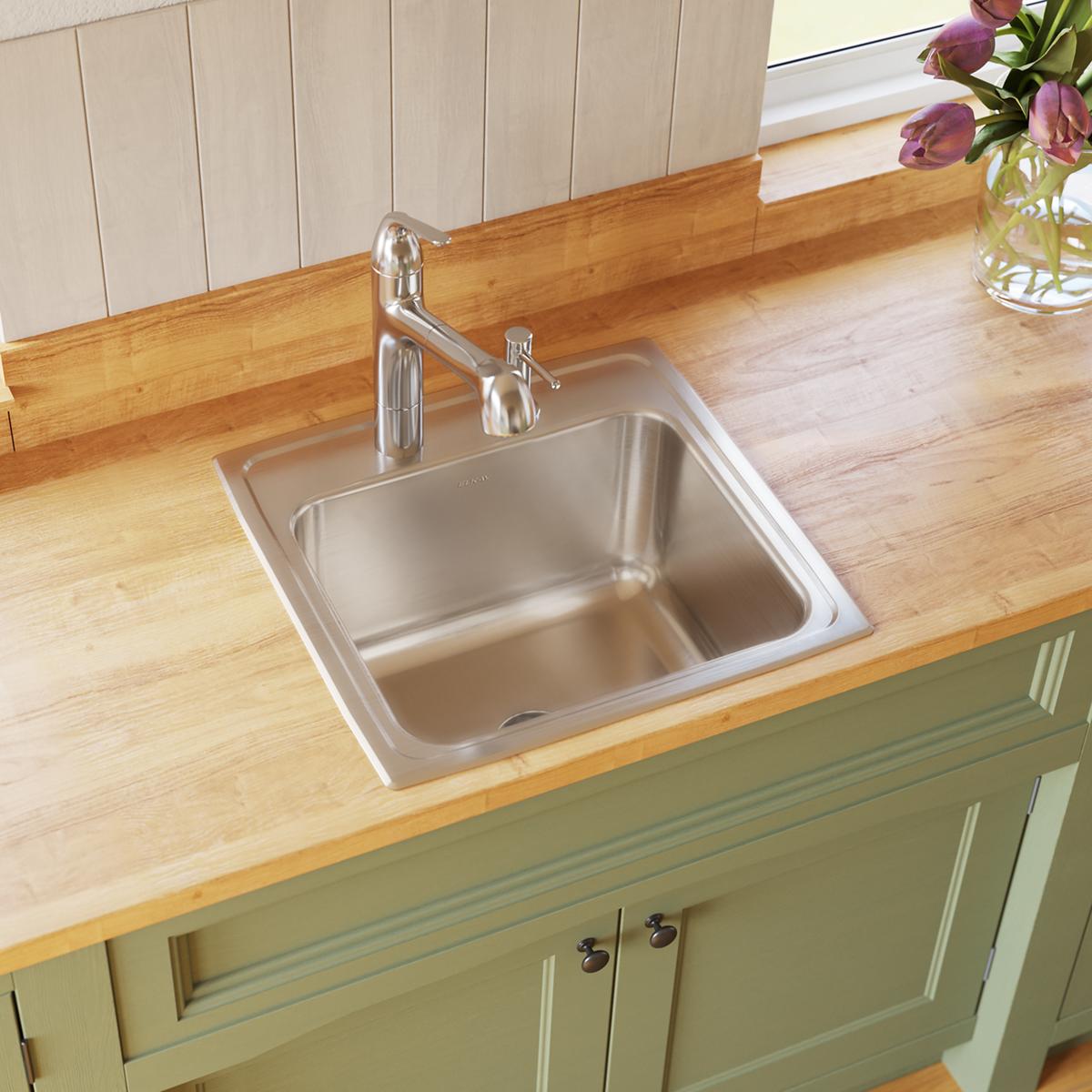 Stainless steel drop-in laundry sink with single bowl and chrome faucet installed in wood countertop.