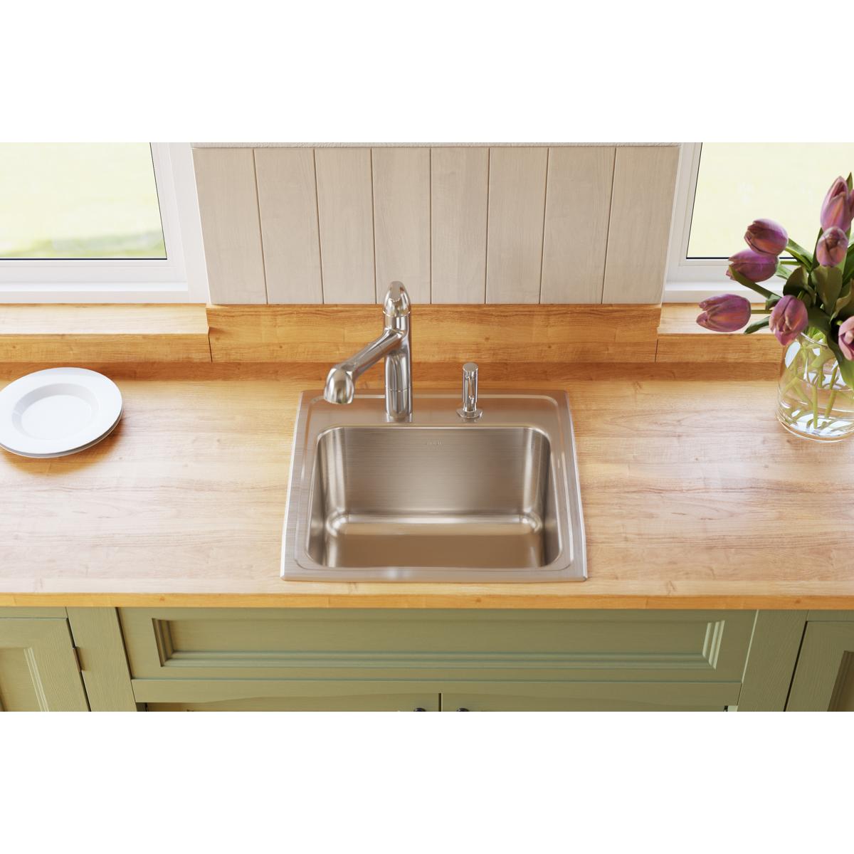 Stainless steel drop-in laundry sink with single bowl and chrome faucet installed in wooden countertop.
