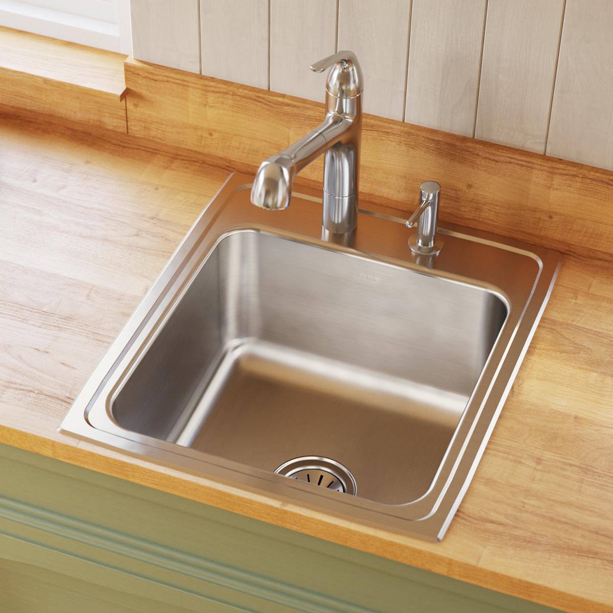 Stainless steel drop-in sink with single bowl, chrome faucet and sprayer installed in wood countertop.