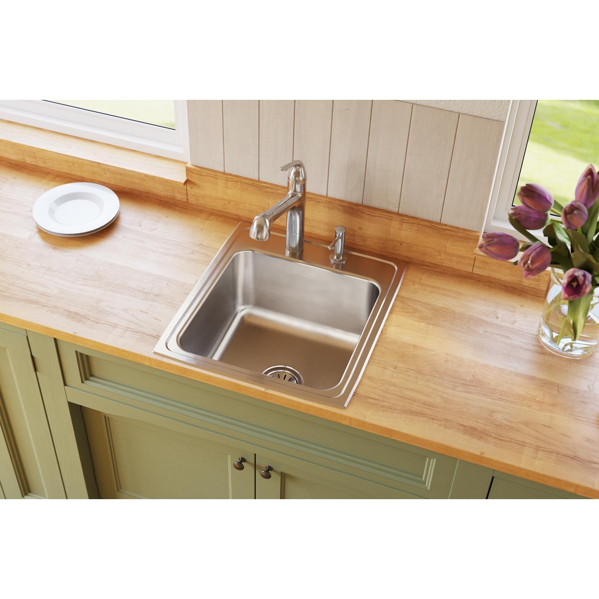Stainless steel drop-in sink with single bowl installed in wooden countertop, shown with faucet and four mounting holes.