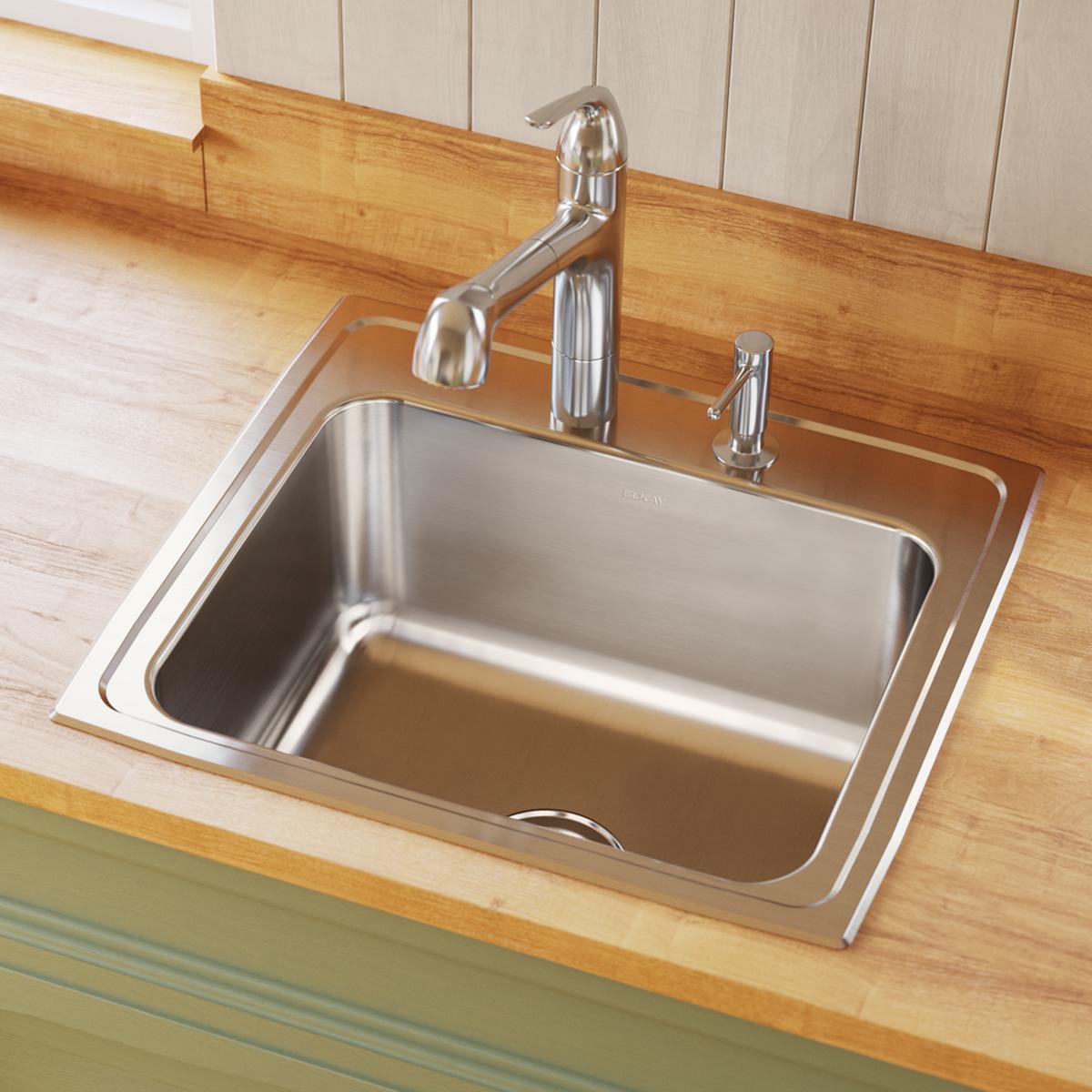 Stainless steel drop-in sink with single bowl, chrome faucet and sprayer installed in wood countertop.