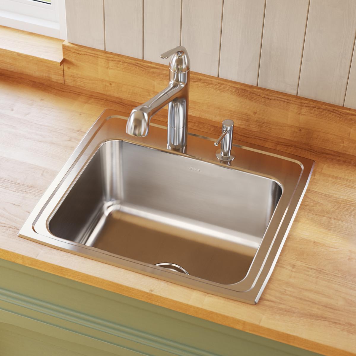 Stainless steel drop-in sink with single bowl, faucet, and sprayer mounted on wood countertop with white cabinetry.