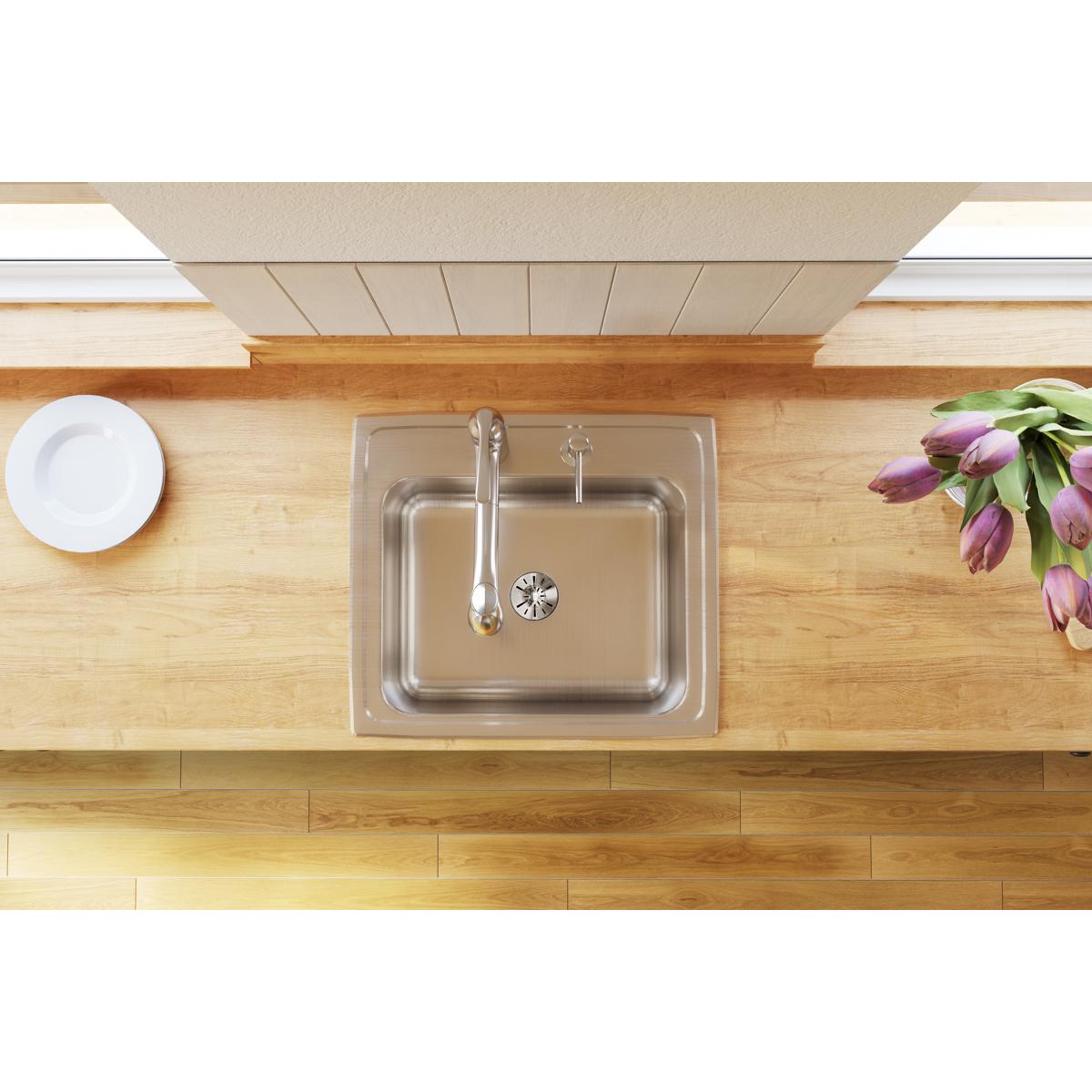 Stainless steel single bowl drop-in sink installed in wood countertop with faucet and drain visible.