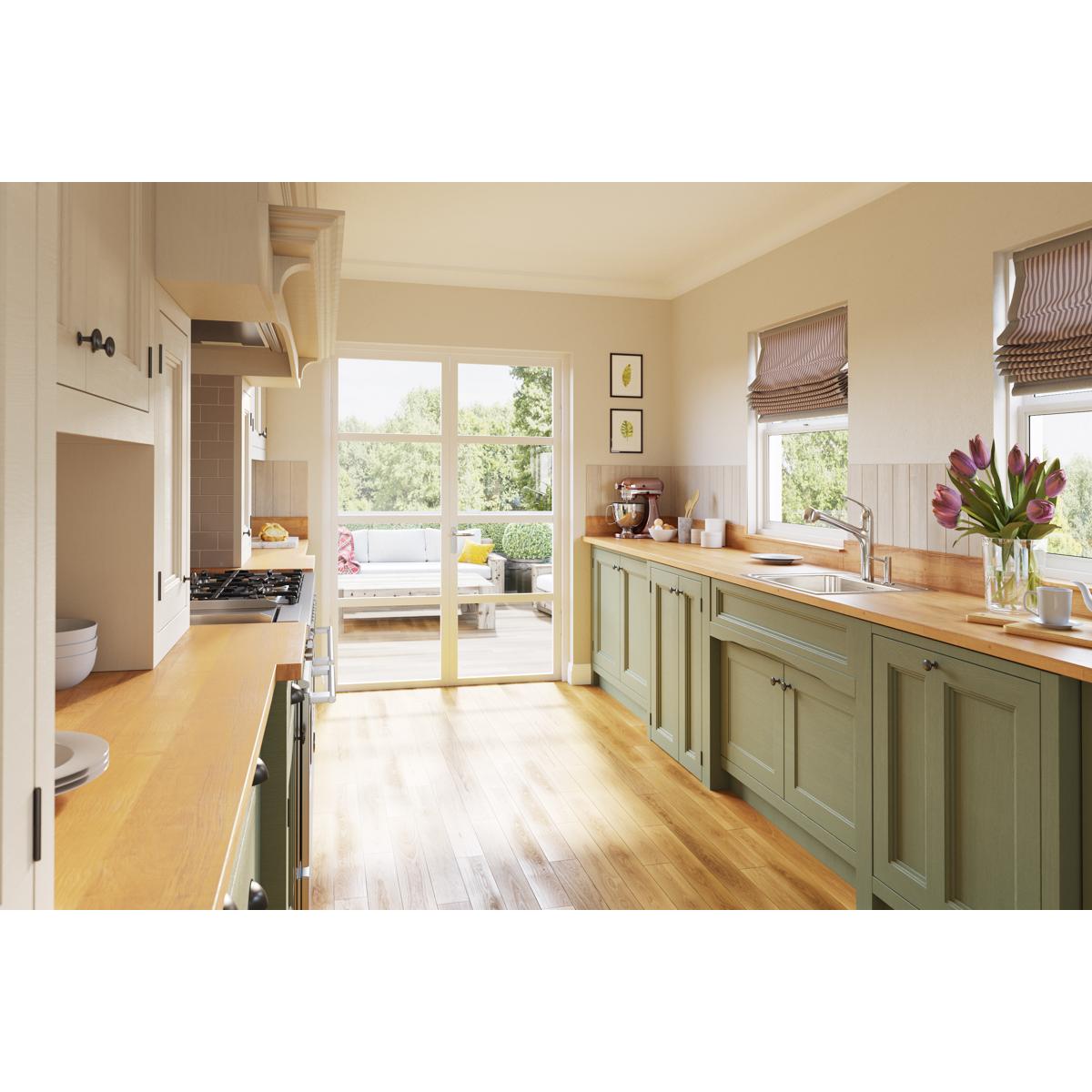 Stainless steel single bowl drop-in sink installed in green kitchen cabinetry with wooden countertop.