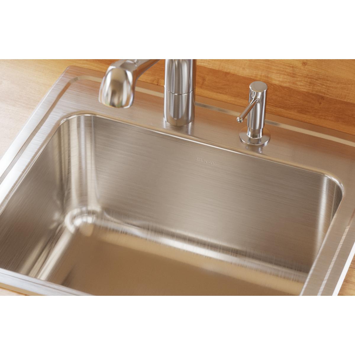 Stainless steel single bowl drop-in sink with brushed finish mounted in wood countertop with faucet.