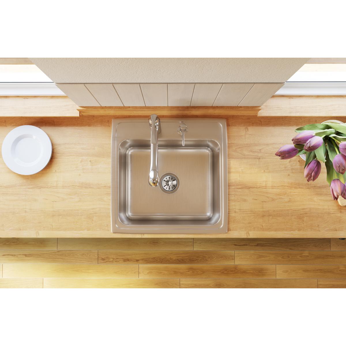 Stainless steel single bowl drop-in sink installed in wooden countertop with chrome faucet and strainer.