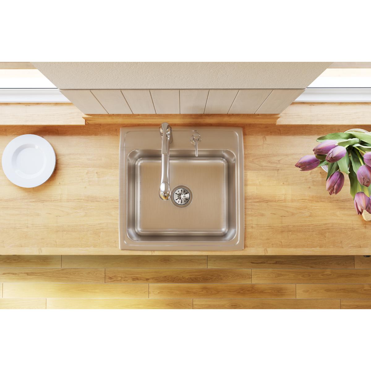 Stainless steel drop-in sink with single bowl and faucet installed in wooden countertop.