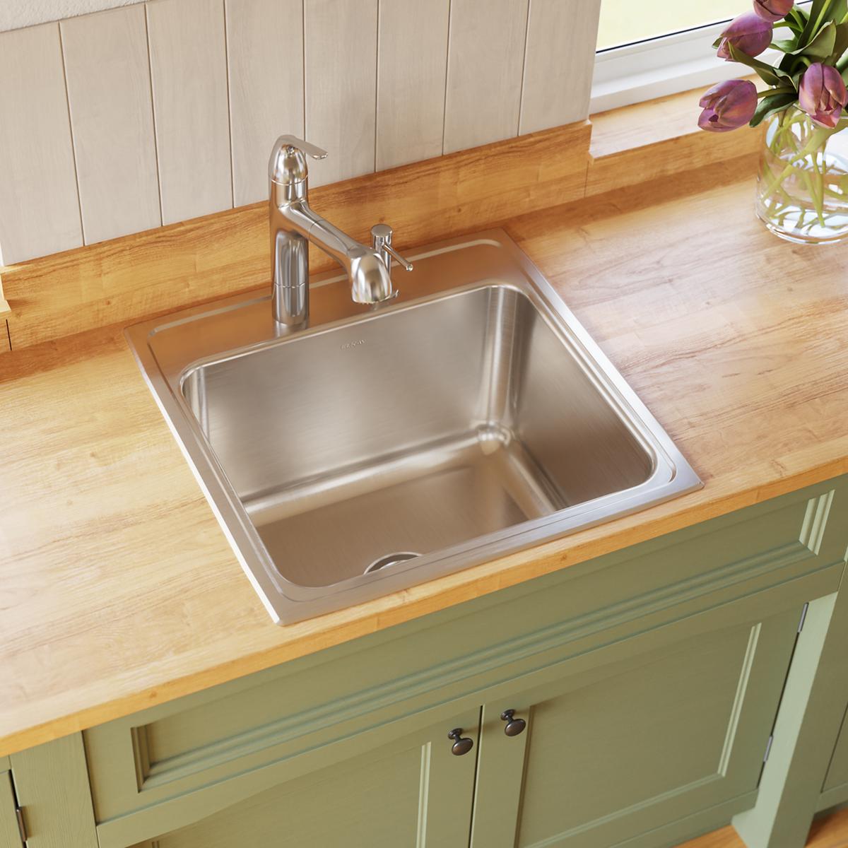 Stainless steel square drop-in sink with single bowl installed in wood countertop with chrome faucet.