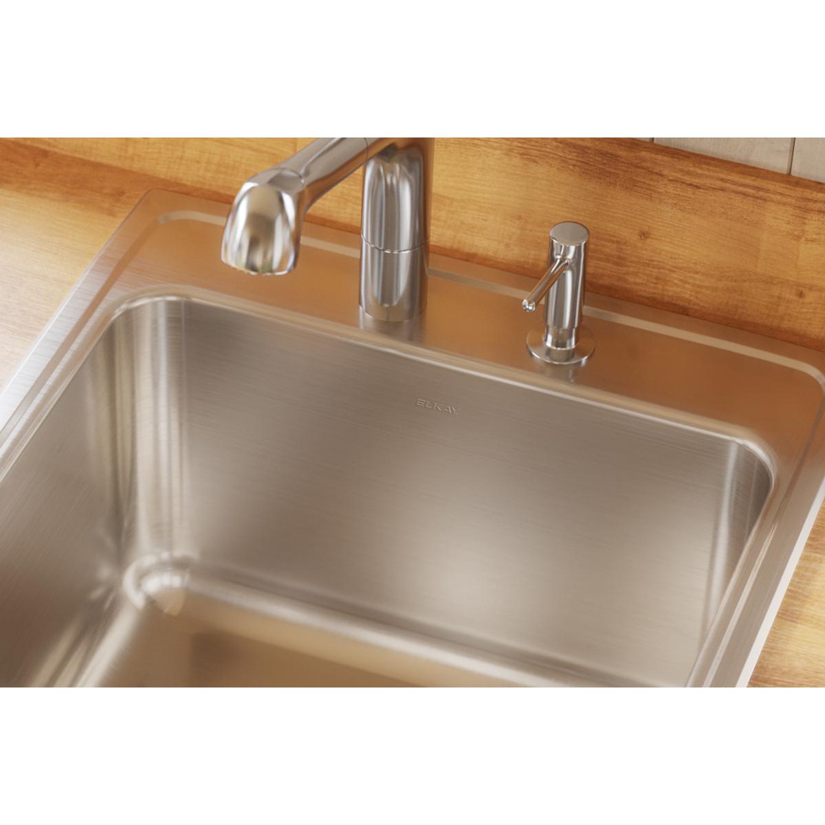 Stainless steel drop-in sink with single bowl and two faucet holes installed in wood countertop.