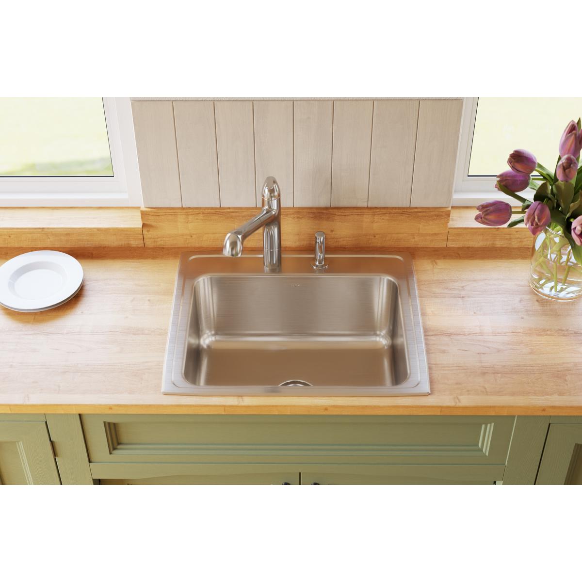 Stainless steel drop-in sink with single bowl installed in wood countertop with chrome faucet.