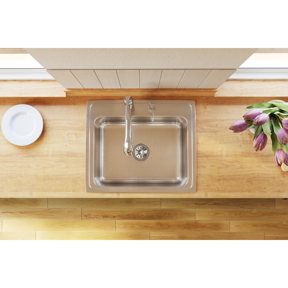 Stainless steel single bowl drop-in sink with rounded edges installed in wood countertop, featuring chrome faucet and three m