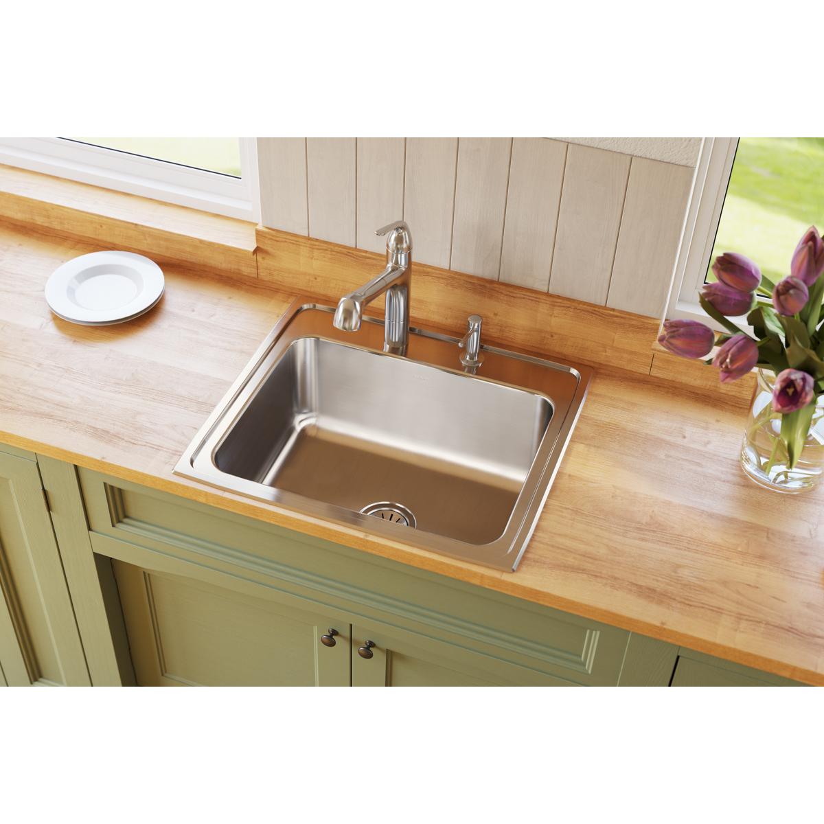 Stainless steel drop-in sink with single bowl and faucet installed in wooden countertop.