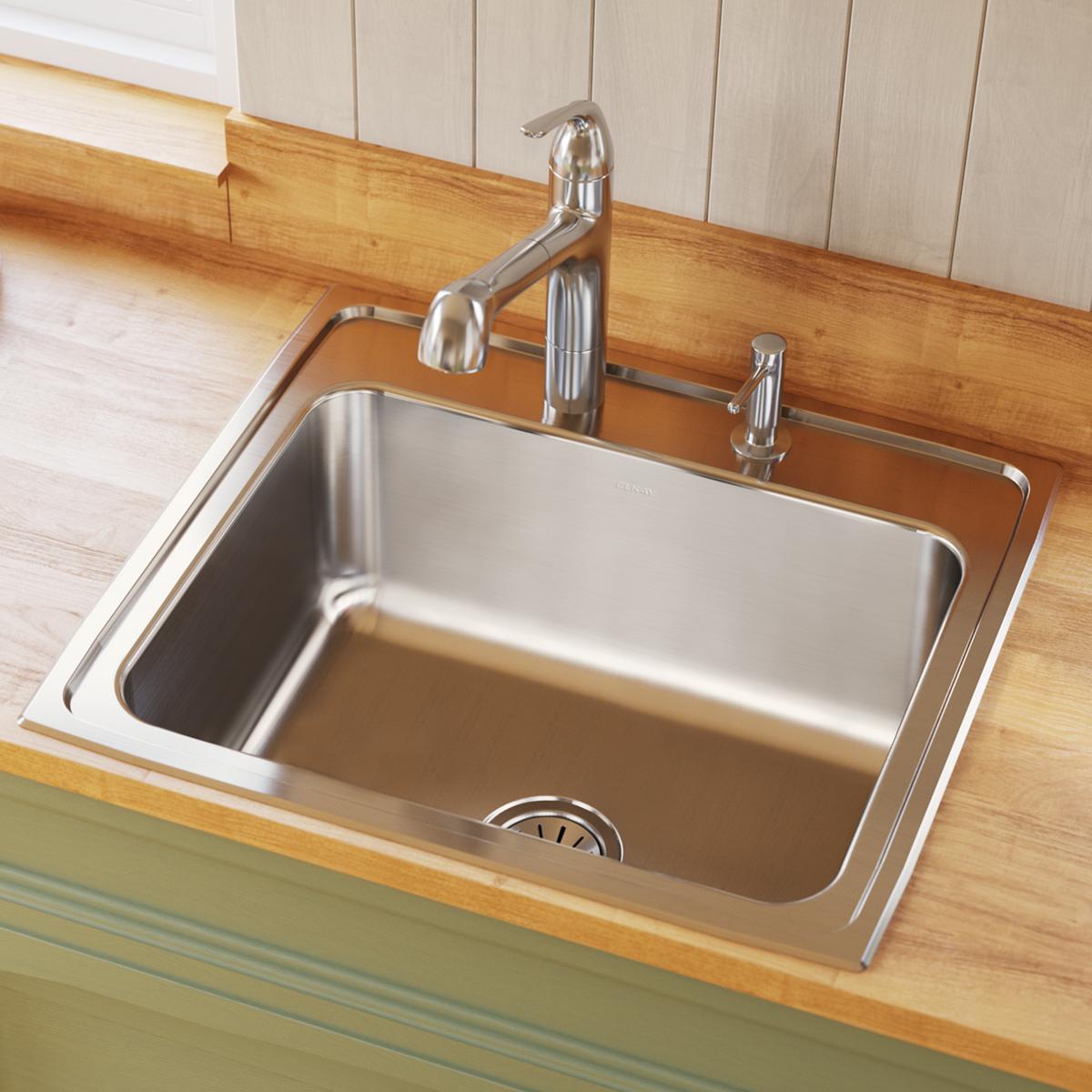 Stainless steel drop-in sink with single bowl, chrome faucet and soap dispenser mounted on wood countertop.