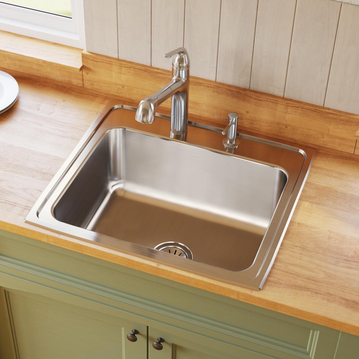 Stainless steel drop-in kitchen sink with single bowl, chrome faucet, and soap dispenser mounted on wood countertop.