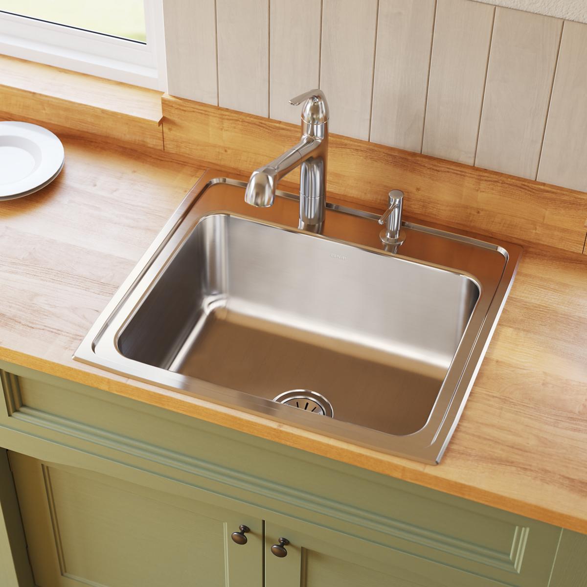 Stainless steel drop-in sink with single bowl, four-hole faucet mounting, and chrome faucet installed on wood countertop.