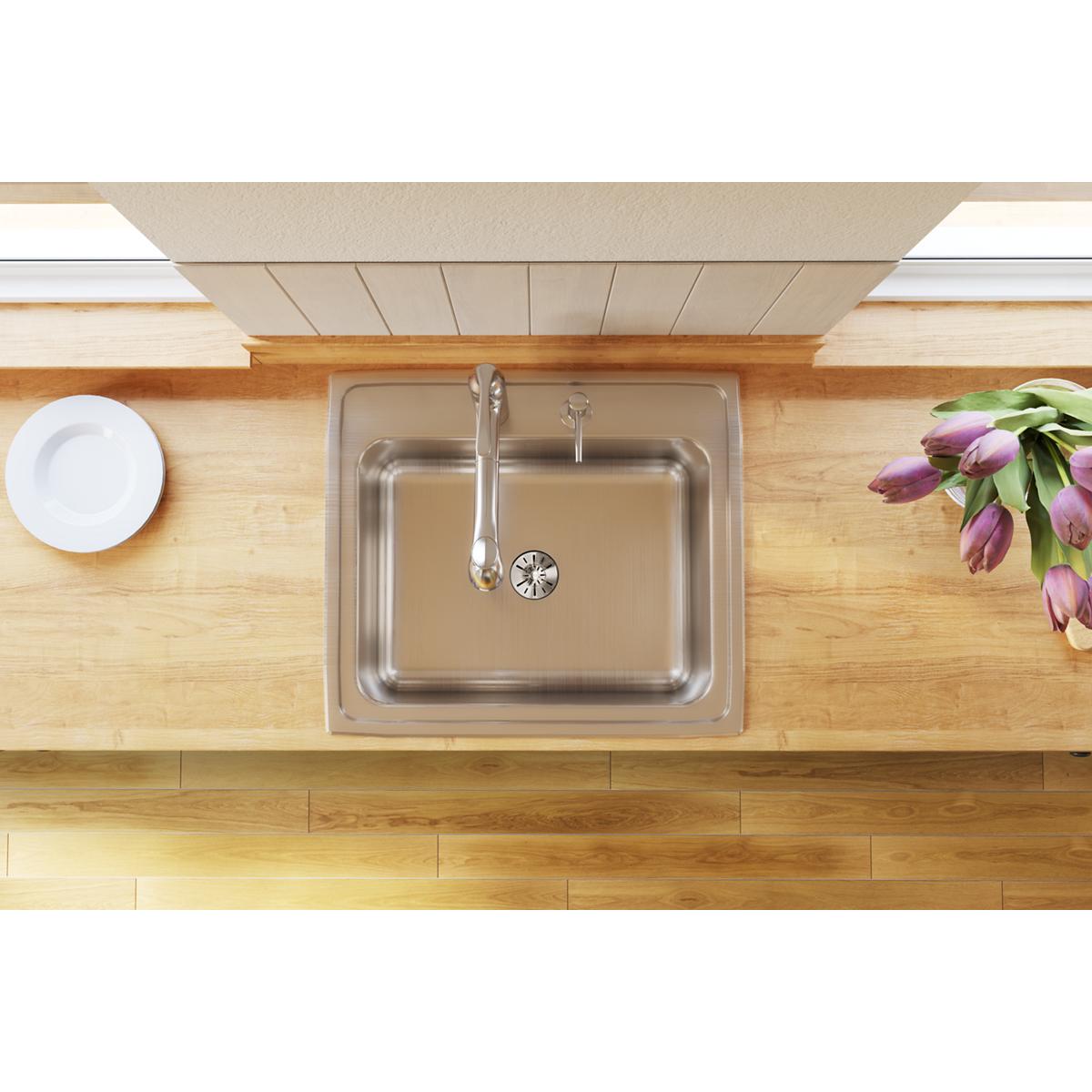 Stainless steel drop-in sink with single bowl, two faucet holes, and drain installed in wooden countertop.