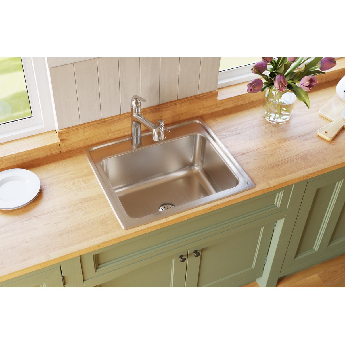 Stainless steel single bowl drop-in sink installed in wooden countertop with chrome faucet and drain visible.