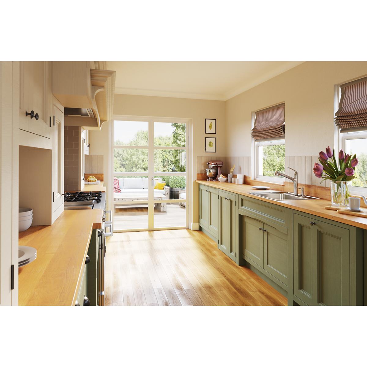 Stainless steel drop-in sink with single bowl and two faucet holes installed in green kitchen cabinetry with wood countertop.