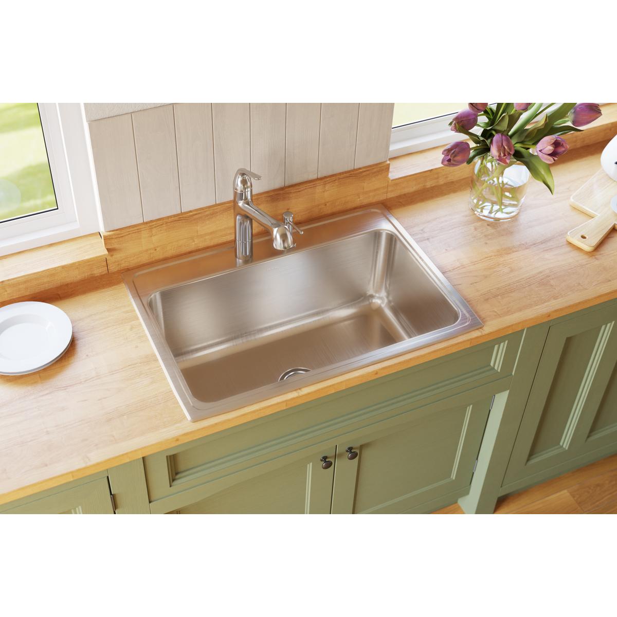 Stainless steel single-bowl drop-in sink with two pre-drilled holes installed in wood countertop.