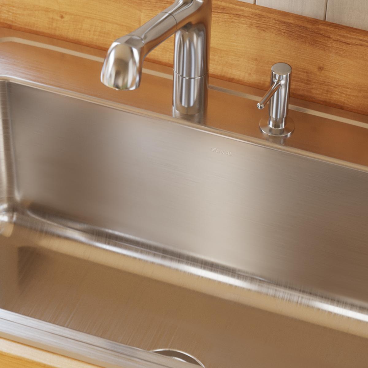 Brushed stainless steel single bowl drop-in sink with three pre-drilled holes and chrome faucet installed in wood countertop.