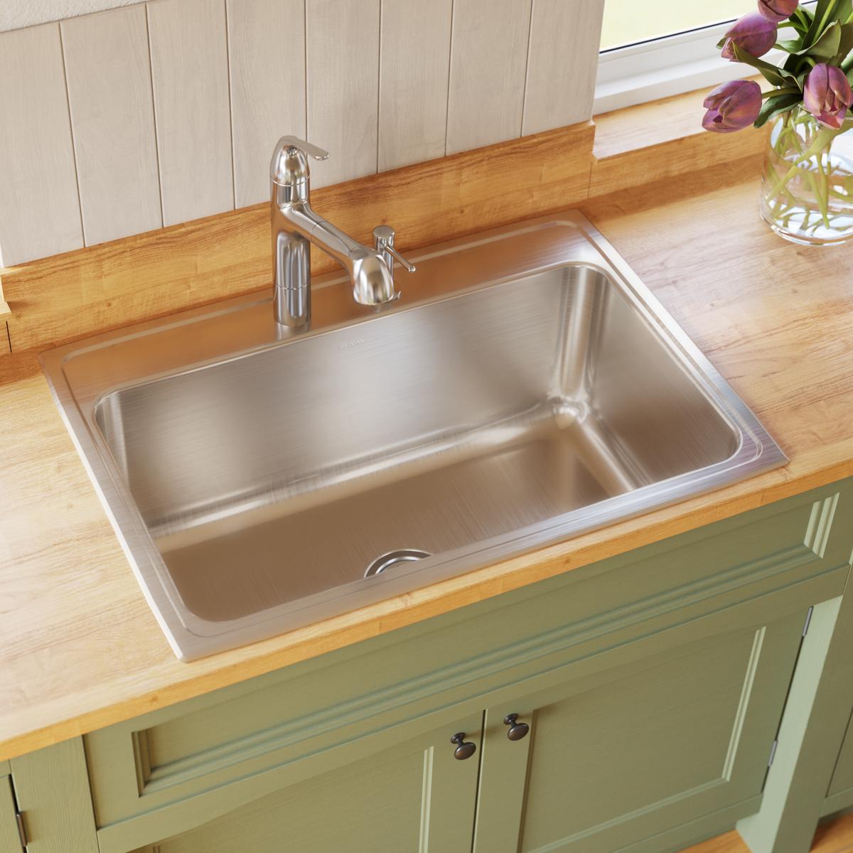 Stainless steel drop-in sink with single bowl and brushed finish installed in wooden countertop with chrome faucet and handle