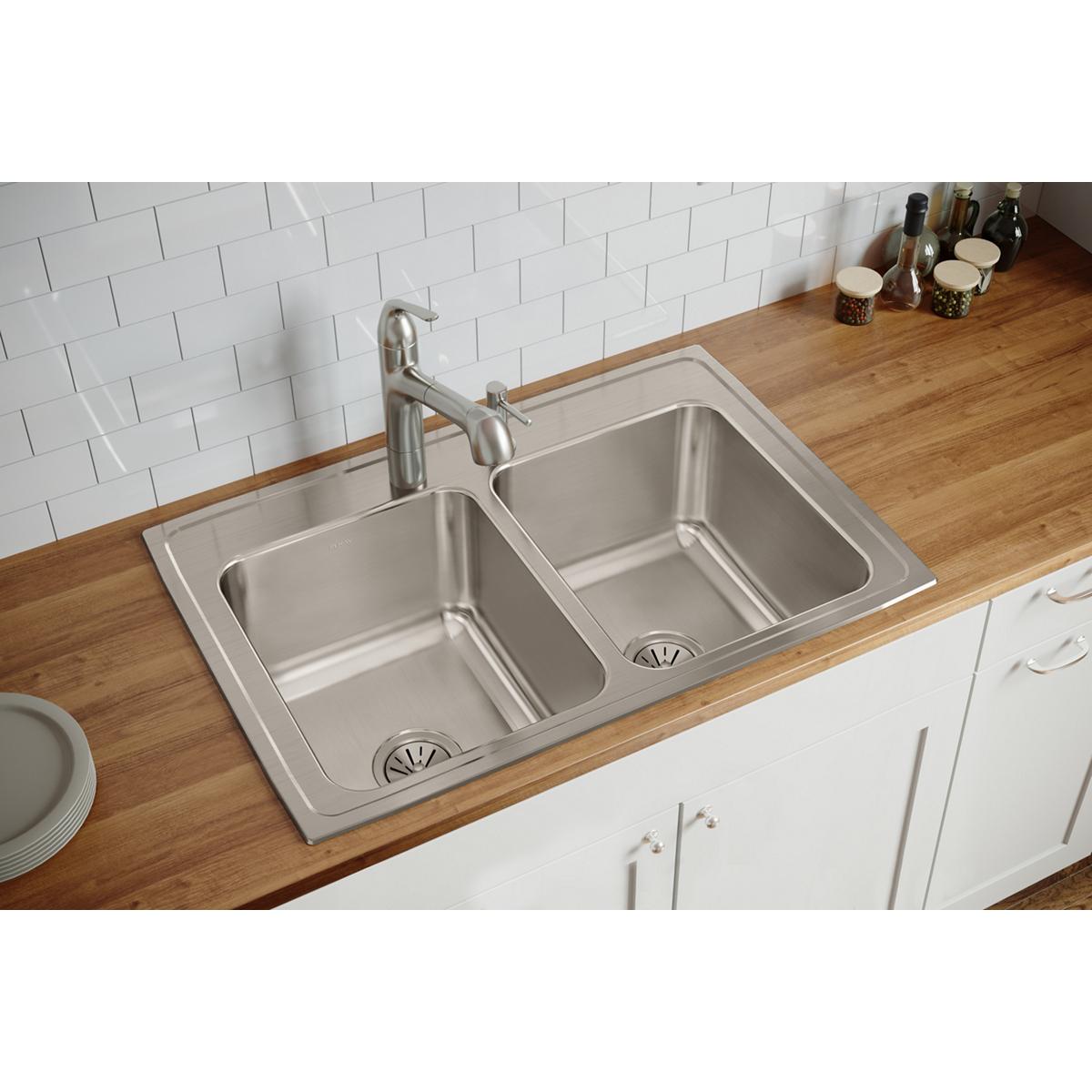 Brushed stainless steel double bowl drop-in sink installed in wooden countertop with single faucet.