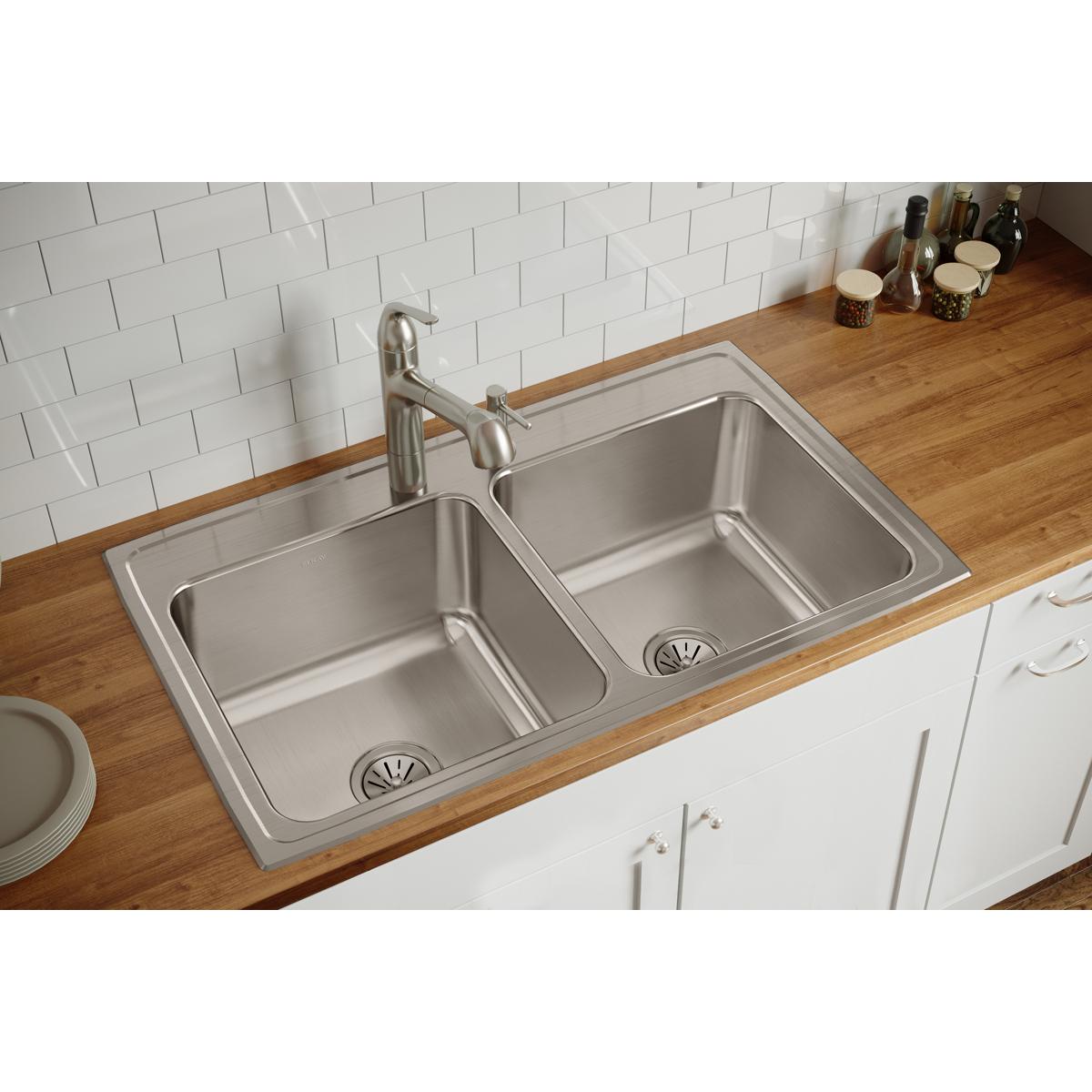 Stainless steel double bowl drop-in sink with two equal-sized basins and drains, installed in wood countertop with chrome fau