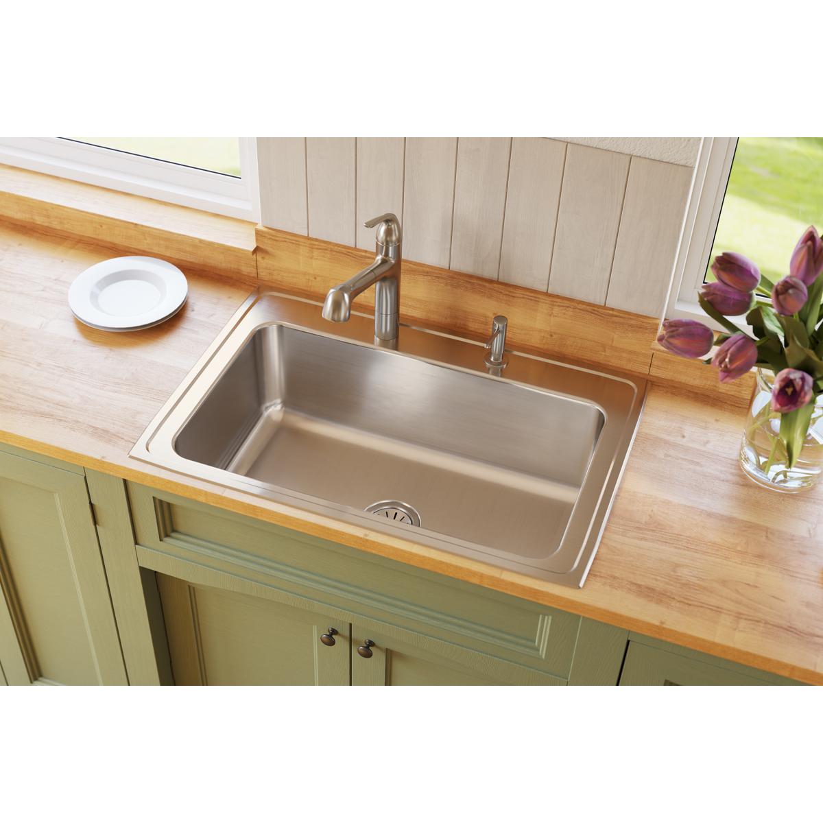 Stainless steel single bowl drop-in sink installed in wooden countertop with faucet and drain visible.
