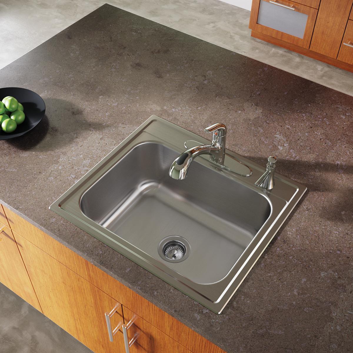 Stainless steel drop-in sink with single bowl and four faucet holes installed in concrete countertop with chrome faucet.
