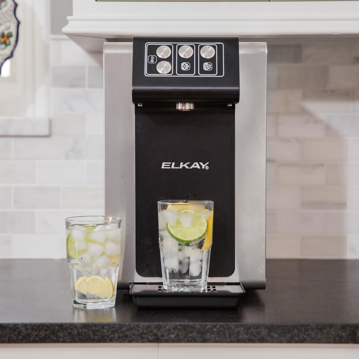 Elkay black and stainless steel water dispenser with control panel and drip tray, dispensing cold water into glass with lime.