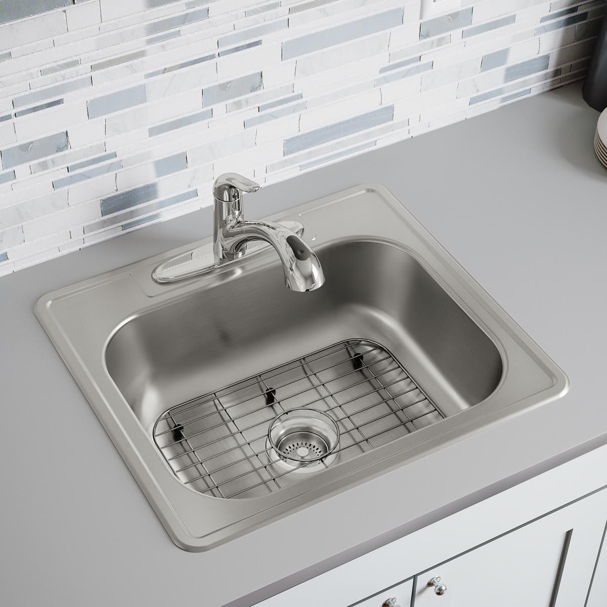 Stainless steel sink grid with rectangular wireframe design and rubber feet, shown installed in kitchen sink basin.