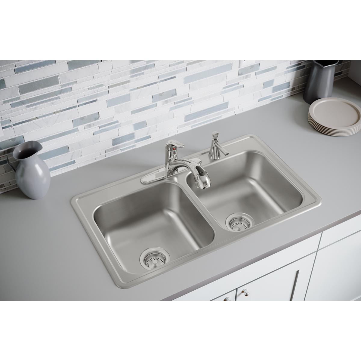 Stainless steel double bowl drop-in sink with equal-sized basins and integrated drainboards installed in white countertop.