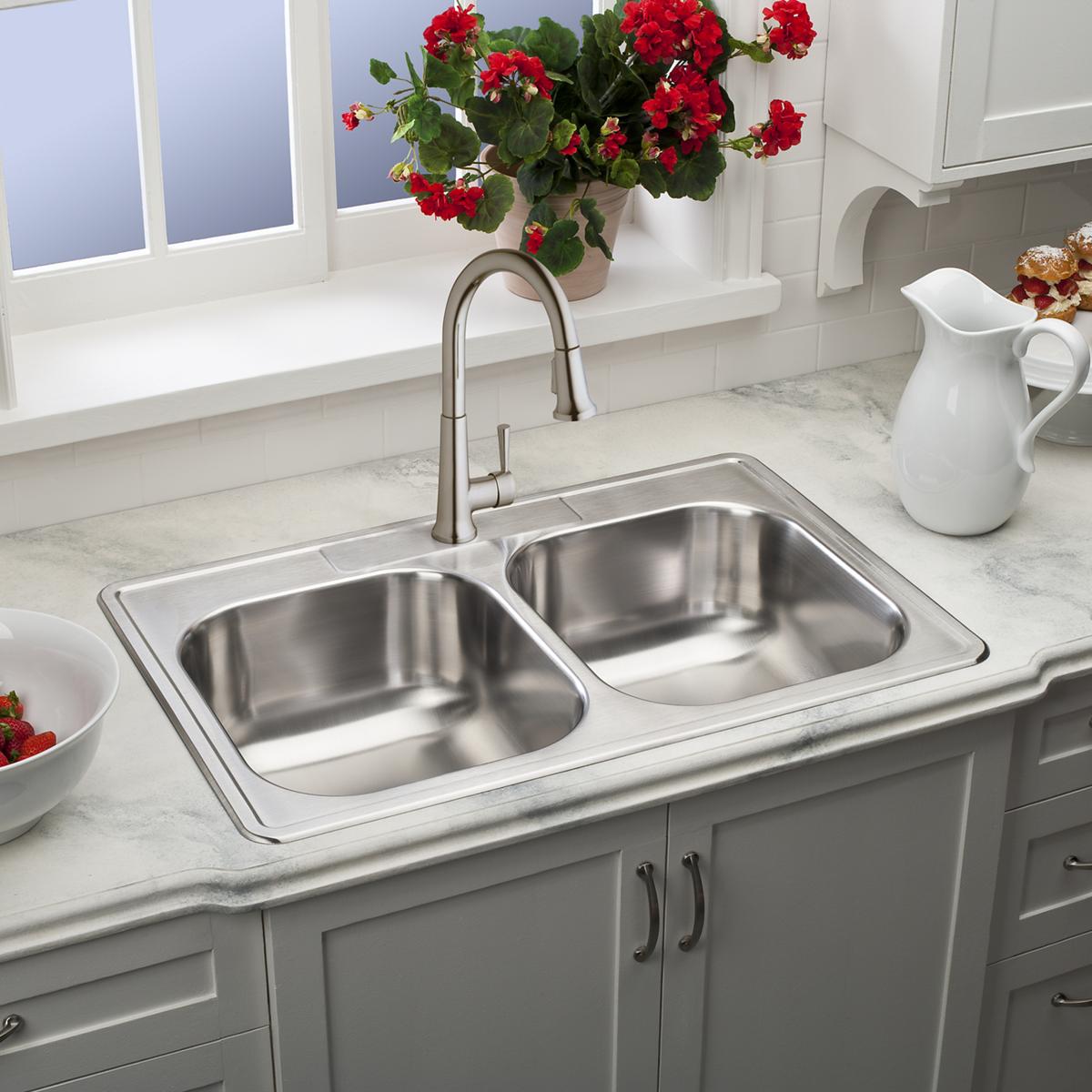 Lustrous steel single-hole pull-down kitchen faucet mounted above a double-basin stainless steel sink.
