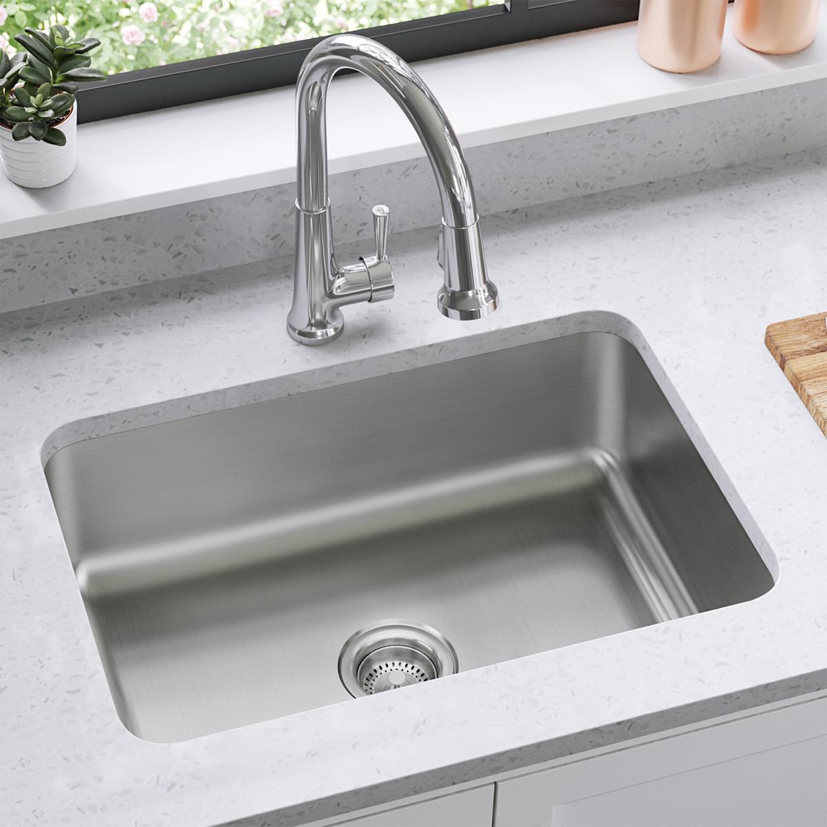 Stainless steel single bowl undermount sink with chrome pull-down faucet installed in white quartz countertop.