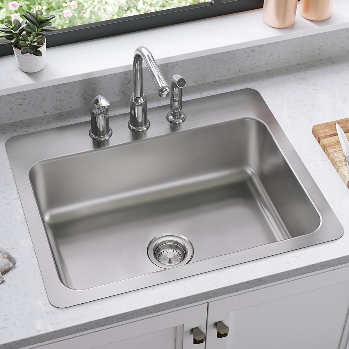 Stainless steel single bowl sink with three-hole faucet mount installed in white countertop.