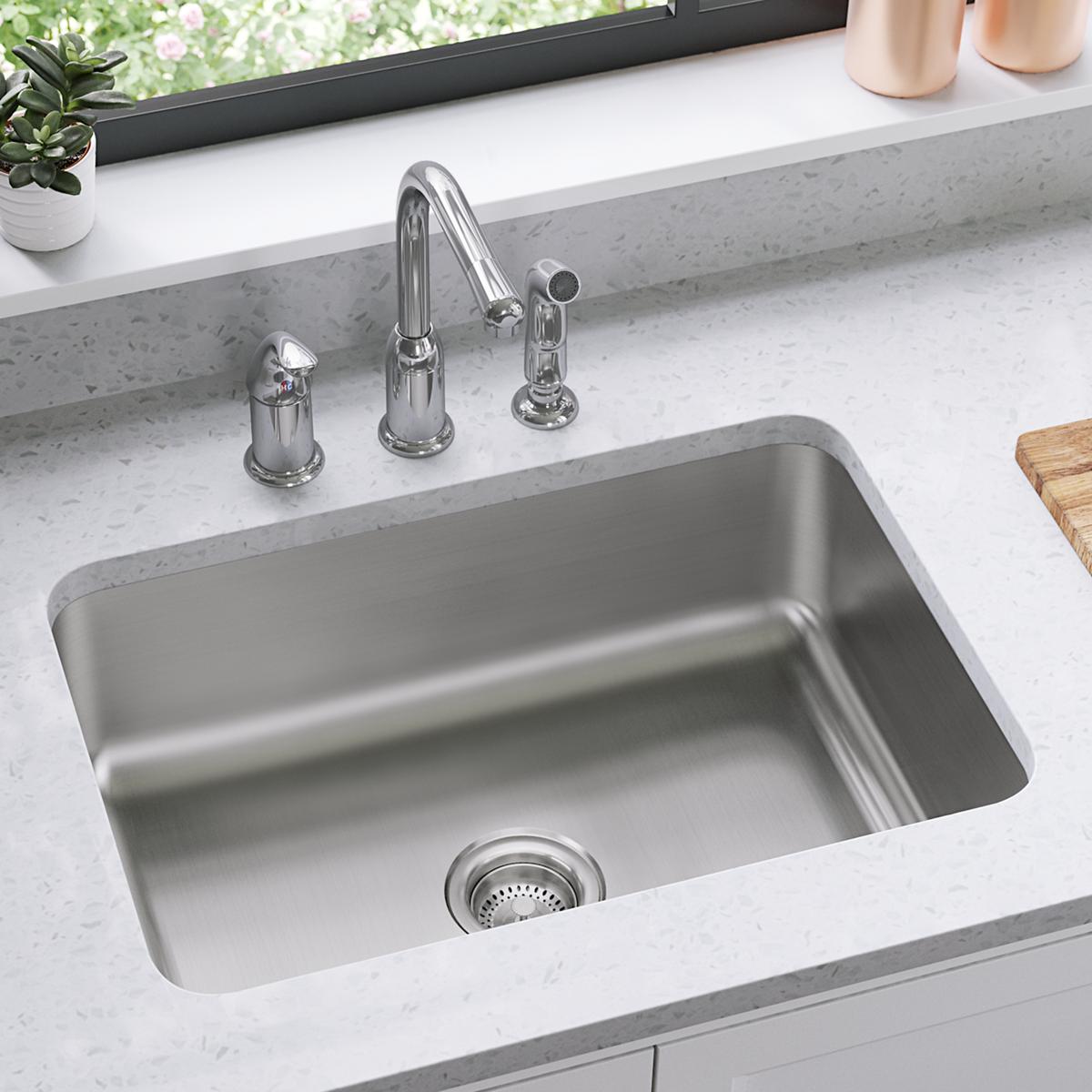 Stainless steel single bowl sink with three-hole faucet mount installed in white countertop.