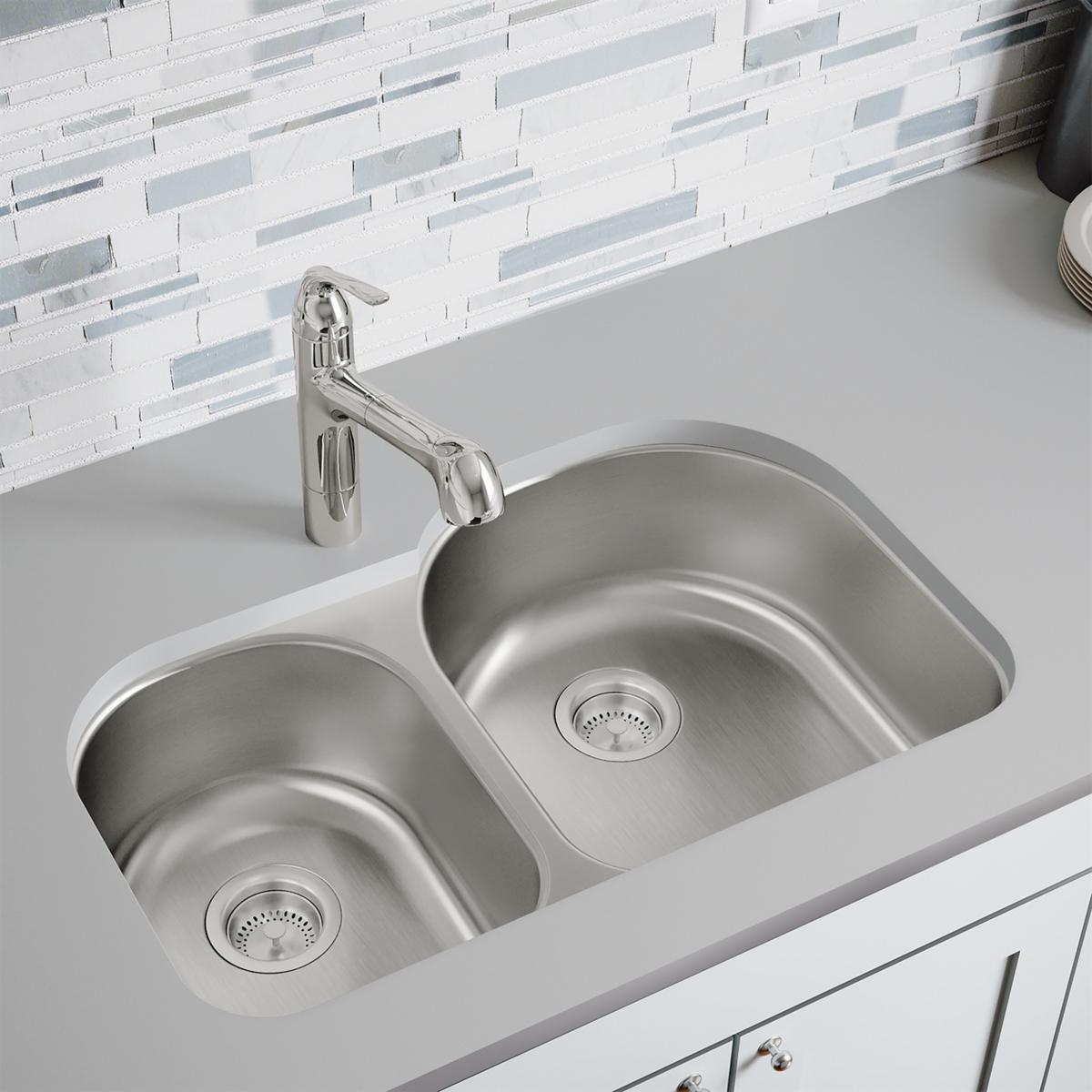 Stainless steel double bowl undermount sink with offset basins and drain strainers installed in white countertop.