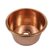 Polished copper round sink with hammered texture interior and drain opening.