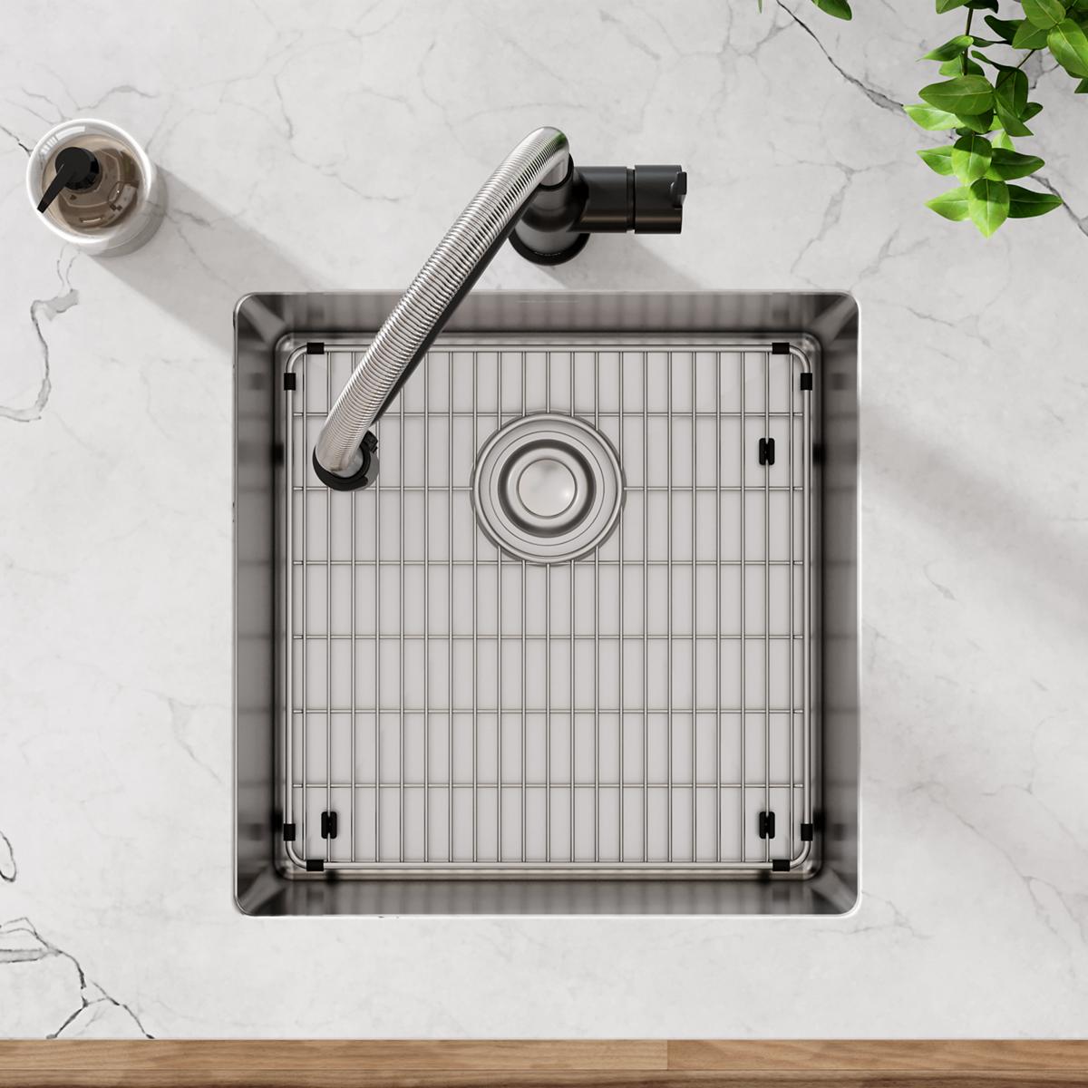 Stainless steel square undermount sink with grid insert, drain, and black faucet viewed from above on marble countertop.