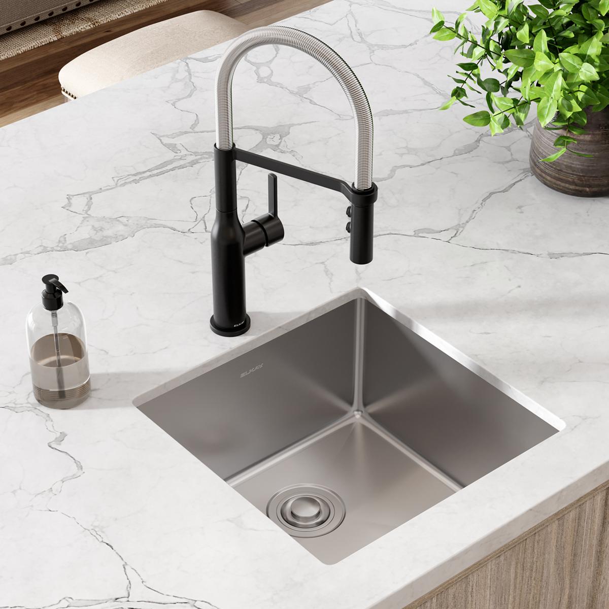 Stainless steel undermount sink with single square bowl installed in white marble countertop, paired with black pull-down fau